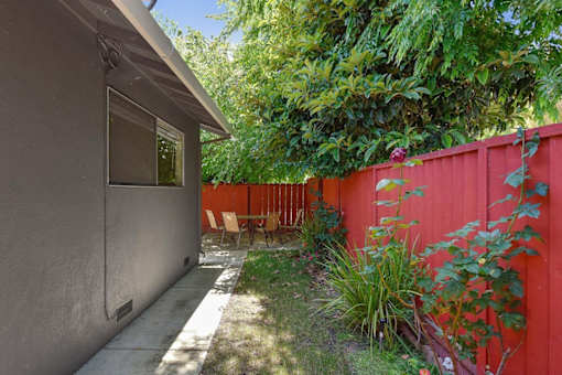 A red fence and a grey wall with a window.