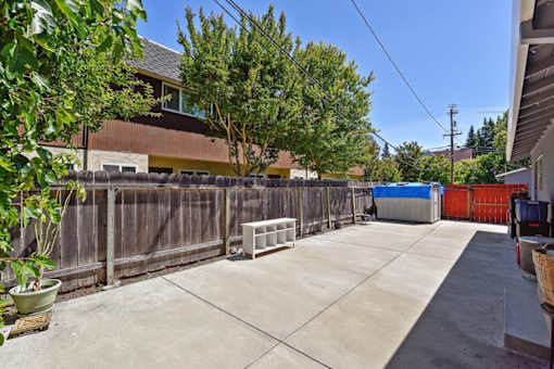 A backyard with a fence, a tree, and a shed.