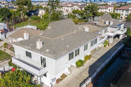 an aerial view of a house with a roof and a body of water