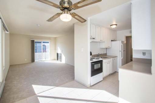 an empty kitchen and living room with a ceiling fan