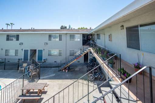 an apartment building with stairs and a patio with bikes and a picnic table