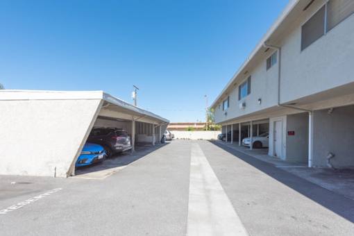 an empty parking lot between two buildings with cars parked