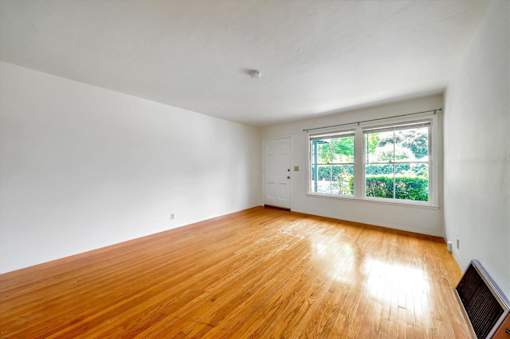 an empty living room with wood floors and a window
