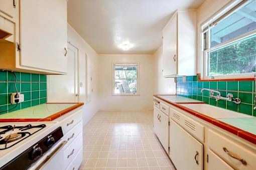 a kitchen with green tile and white cabinets