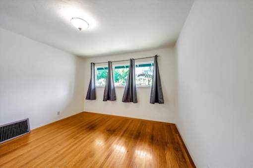 an empty room with three windows and a wood floor