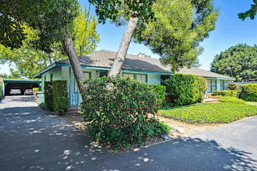 a green house with a tree in front of it