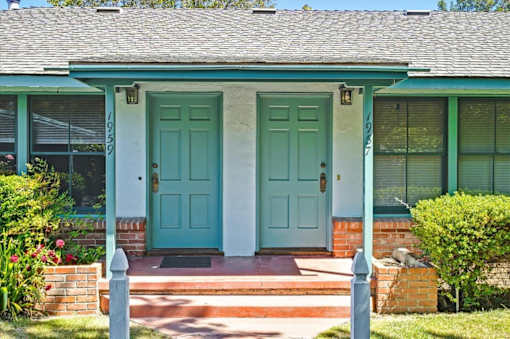 a blue house with two doors and a porch
