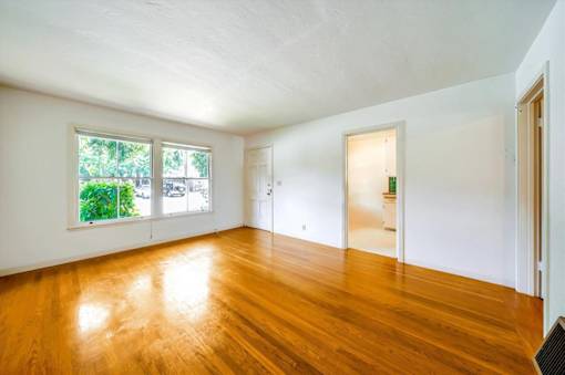 an empty living room with wood floors and a window