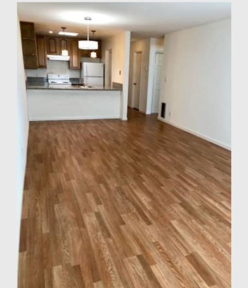 an empty living room and kitchen with wood flooring
