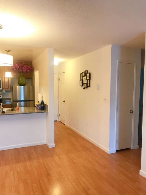 an empty living room and kitchen with a wood floor