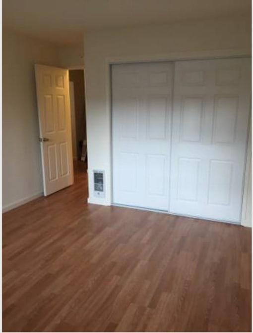 an empty living room with wood floors and a door