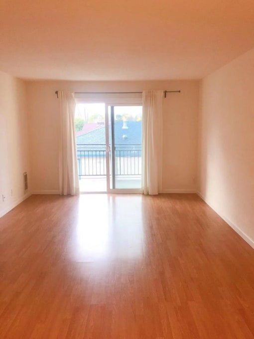 an empty living room with wood floors and a balcony