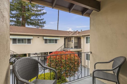a patio with two chairs and a balcony overlooking a building