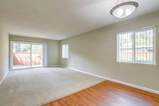 an empty living room with wood floors and a large window