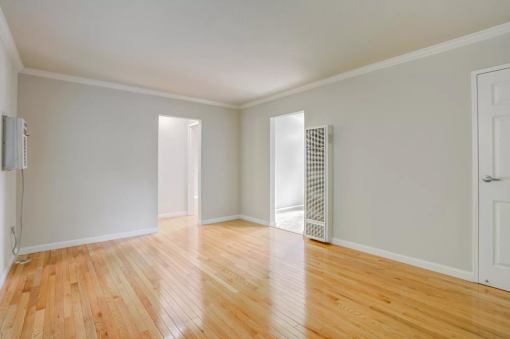 an empty living room with wood floors and white walls