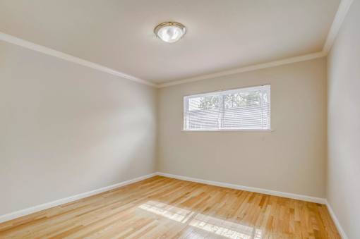 an empty room with wood floors and a window