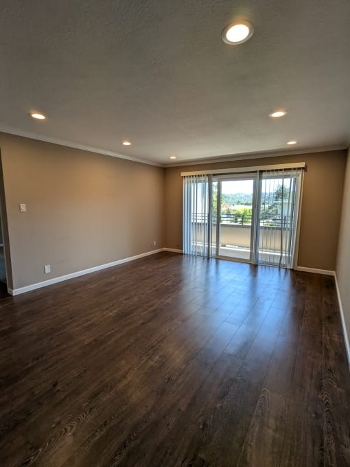 an empty living room with wood floors and a sliding glass door