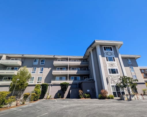 an apartment building with a parking lot and a blue sky