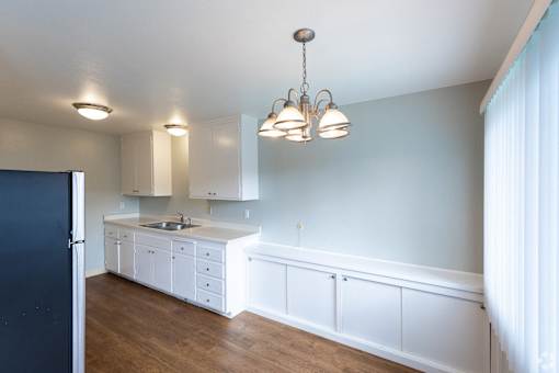 a kitchen with white cabinets and a counter top and a refrigerator