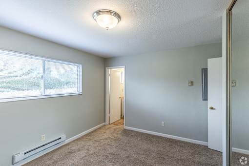 an empty room with a large window and a door to a hallway