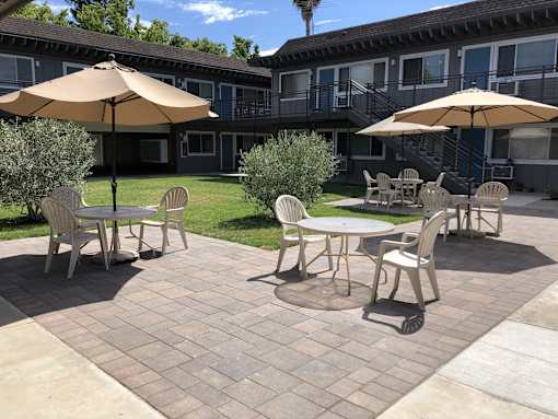 a patio with tables and umbrellas in front of a building