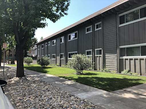 a black building with a sidewalk and grass in front of it
