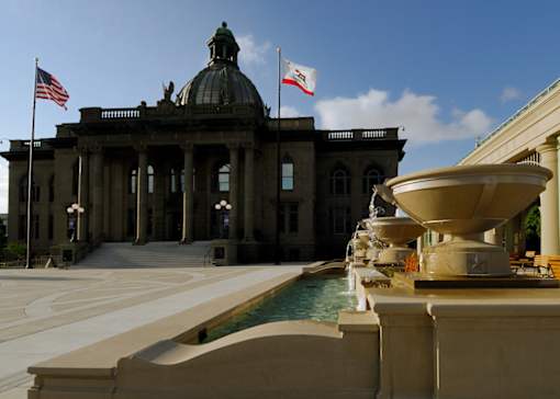 a fountain in front of a building with two flags