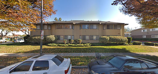 A beige two-story house with a white car parked in front.