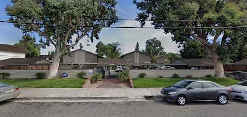 A street view of a residential area with cars parked on the side of the road.