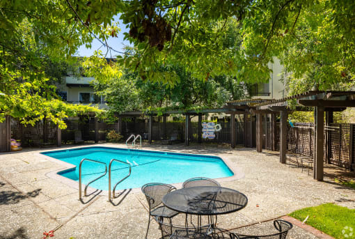 a swimming pool in a backyard with a table and chairs