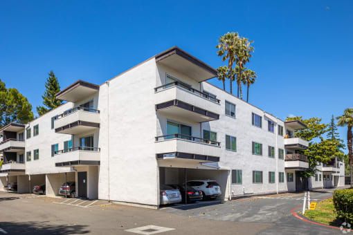 a white apartment building with cars parked in front of it