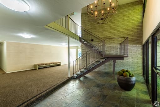 a lobby with a staircase and a bowl of fruit