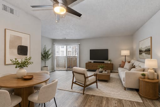 A living room with a wooden table and chairs, a couch, and a television.