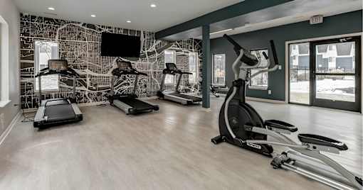 A gym with treadmills, elliptical machines, and a television.