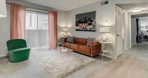 A living room with a green chair, a brown sofa, and a white side table.