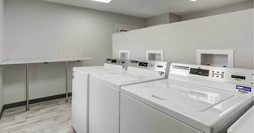 A row of white washing machines in a laundromat.