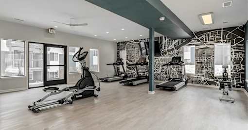 A spacious gym with a variety of equipment including treadmills, stationary bikes, and weight machines.