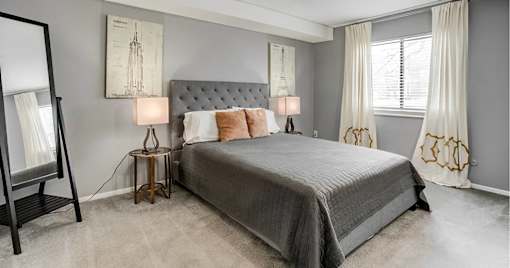 A bedroom with a large bed and two lamps.