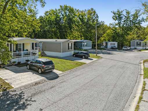 A car is parked on the side of a road in front of a house.