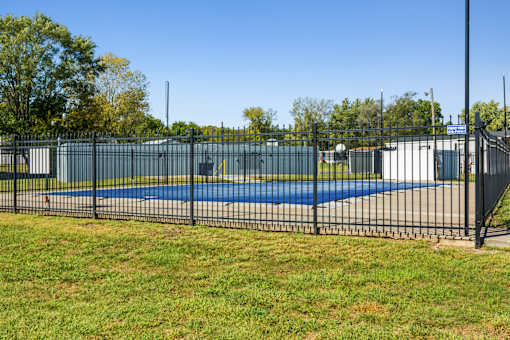 A black fence surrounds a blue pool.
