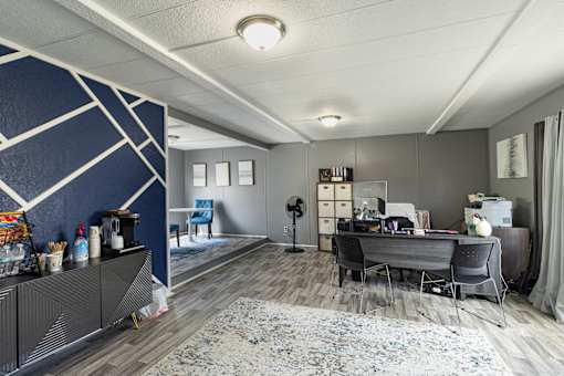 A room with a desk, chairs, and a fan.