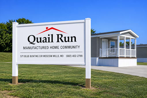 A sign for Quail Run Manufactured Home Community with a house in the background.