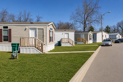 A row of mobile homes with a car parked in front of the first one.