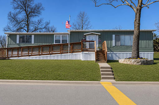 A house with a flag on the roof and a tree in front.