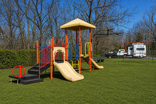 A playground with a yellow slide and a red and blue play structure.