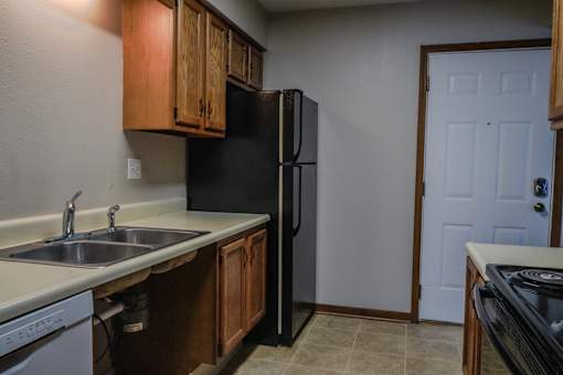 A kitchen with a black refrigerator and a white door.