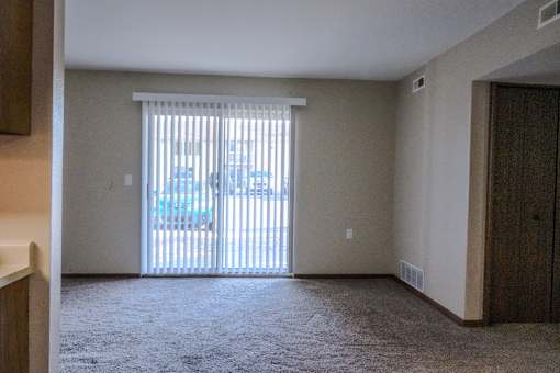 A room with a carpeted floor and a sliding glass door.