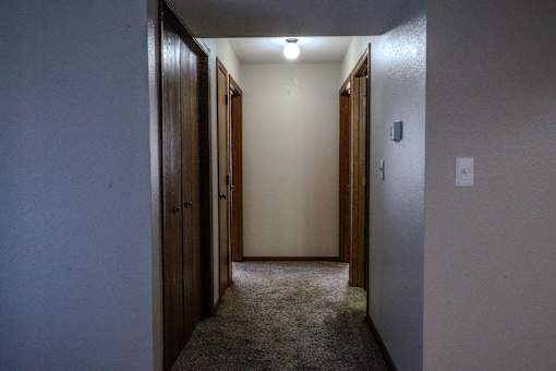 A hallway with carpeted floor and two doors on the left.