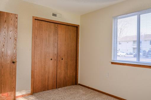 A room with a window and a pair of wooden doors.