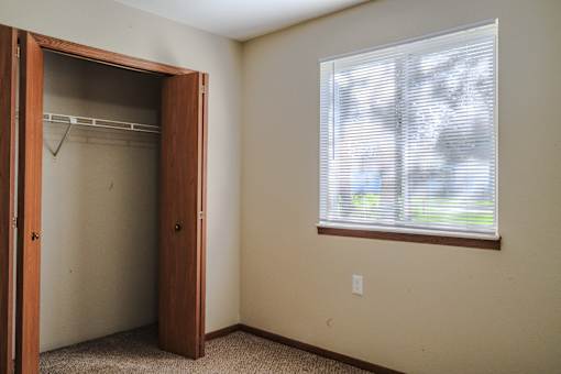 A room with a brown door and a window with blinds.